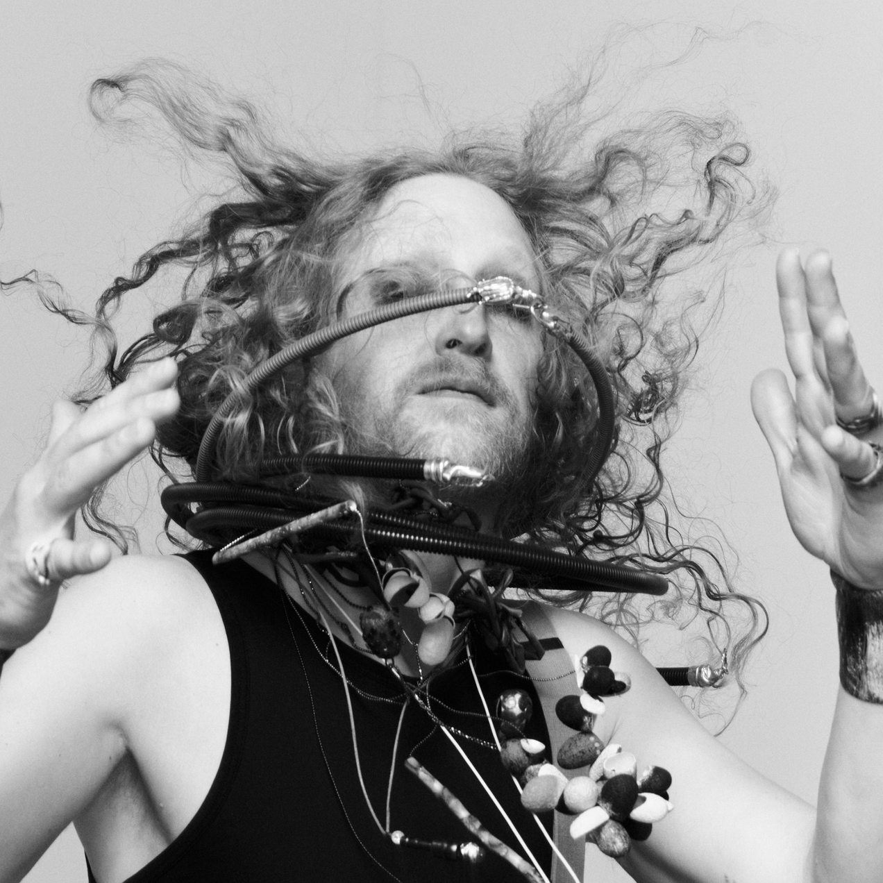 Artist Georg Petermichl wears bracelets, necklaces by Ela Nord over a black tank top, in a quick movement jewelry and hair fly up
