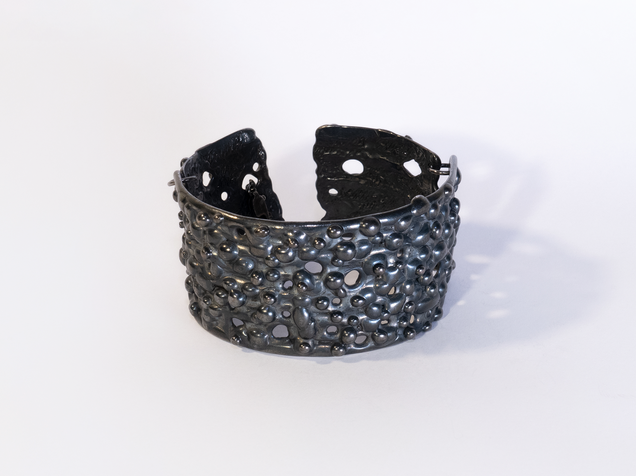 Blackened silver bangle with a nub surface texture like chameleon skin