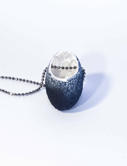 Necklace with a black silk cocoon pendant whose white inside is filled with small glass balls, the chain is made of silver