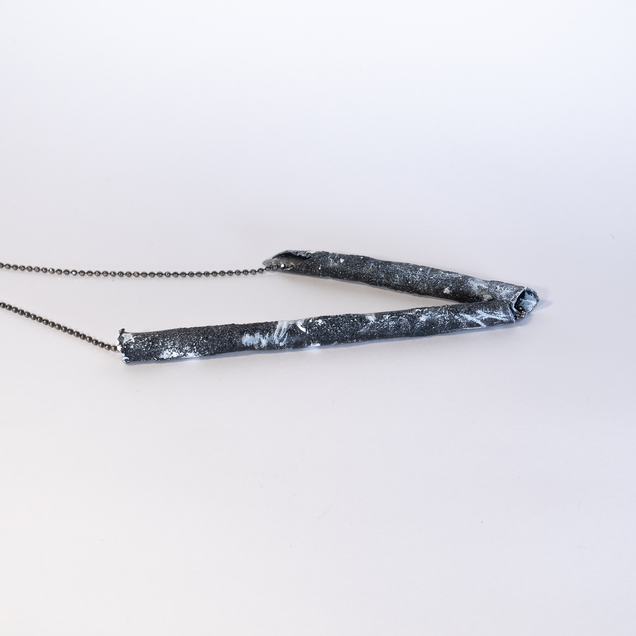 Silver necklace with a two black tubes, looking like a piece of coal