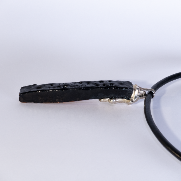 Anhaenger aus einem länglichen schwarz glasierten Keramikstück mit einer Kappe aus Silber, die Glasur "Fat Lava" sieht wie die Mondoberfläche aus 