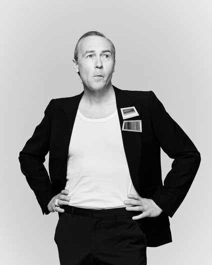 Artist Robert Jelinek wears two brooches on the lapel of the black jacket and sunglasses, his hair is strictly combed back, he asks for something