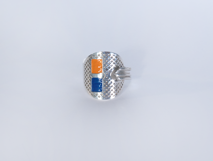 Silberner Schlüssel, der zu einem Ring gebogen ist, zwei rechteckige Flächen sind mit orange und dunkelblauem Emaille gefüllt