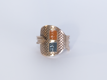 Bronze Schlüssel, der zu einem Ring gebogen ist, zwei rechteckige Flächen sind mit dunkelgrünem und ocker Emaille gefüllt