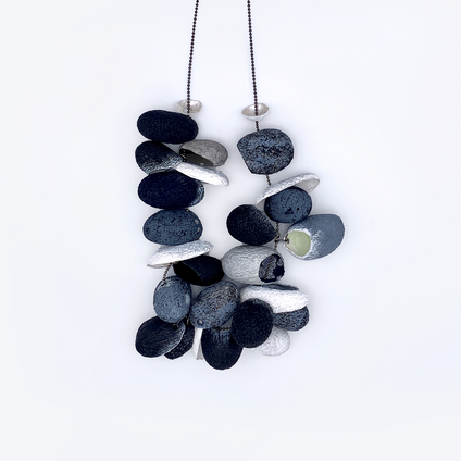 Long silver necklace with 19 threaded silk cocoons open at the front, painted on the outside in shades of grey, black and white