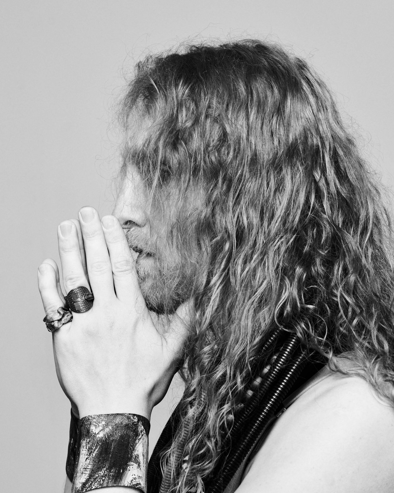 Künstler Georg Petermichl trägt Armbänder, Ringe und Ketten von Ela Nord über einem schwarzen Tank Top, er faltet die Hände vor dem Gesicht