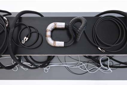 In the exhibition Mulberry Tubes, jewellery artist Michaela Rapp presents works from the two collections BRAZIL and IMAGO, additionally, jewellery pieces created in collaboration with visual artist friends. The installation of havy and small black and grey tube-necklaces is lying on a low bench standing on grey paper that is placed on the wall and the floor.